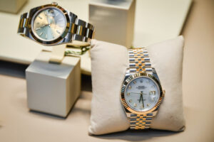 Rolex watches available for collateral loans, displayed on a stand and cushion with a stainless steel and gold bracelet and diamond-accented dial.