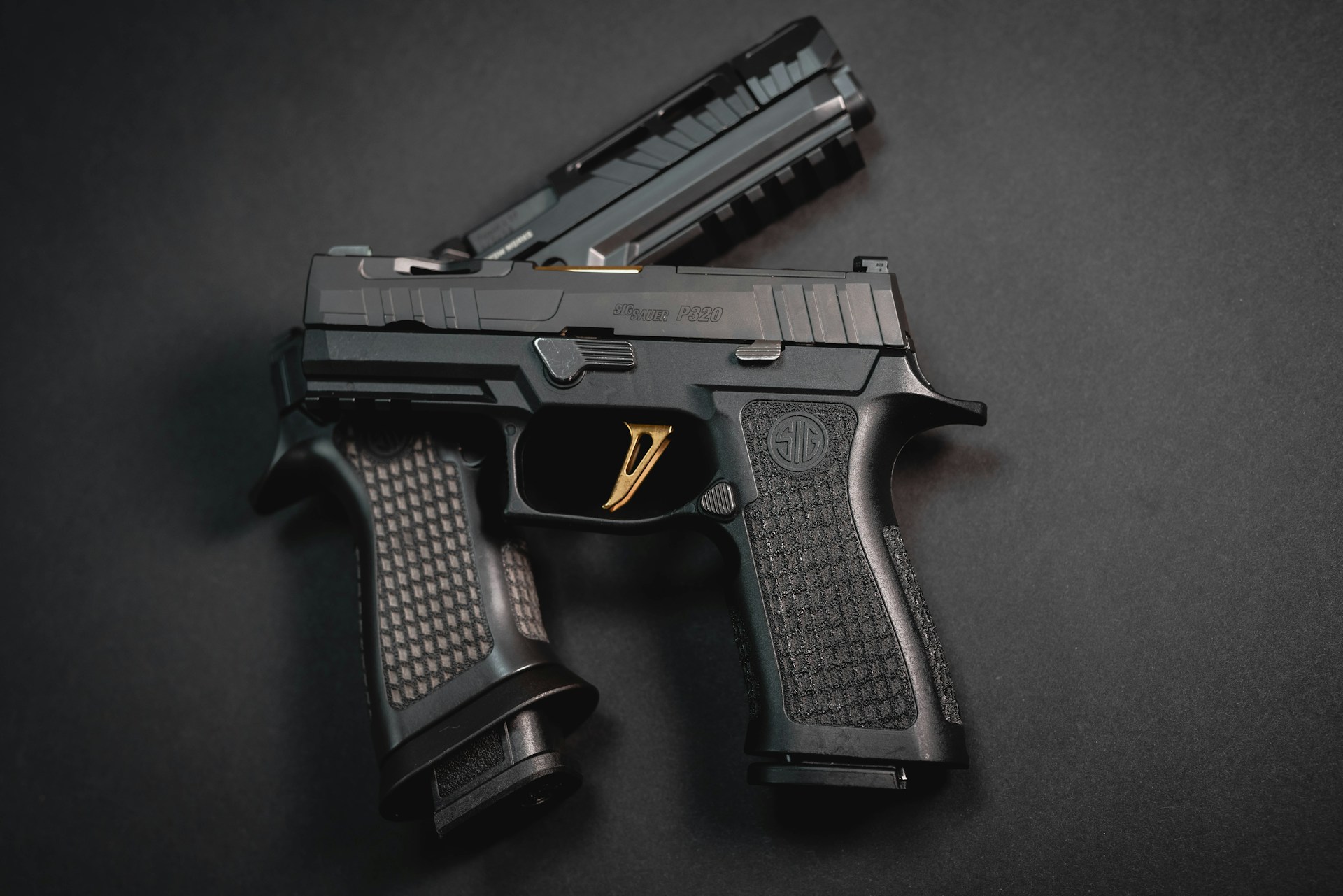 Sig Sauer P320 semi-automatic pistol with a textured grip and a gold trigger on a dark background.