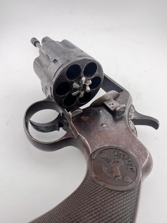 Close-up view of a vintage Colt D.A. .41 “New Army and Navy” Revolver with its cylinder swung open, revealing the chamber interiors and the Colt logo on the grip.