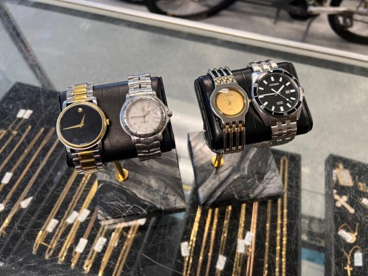 A collection of high-quality wristwatches displayed on a stand, including brands like Movado, Citizen, and Geneva, featuring classic and modern designs with gold and silver accents, available for purchase at Dixie Pawn in Hollywood, Florida.