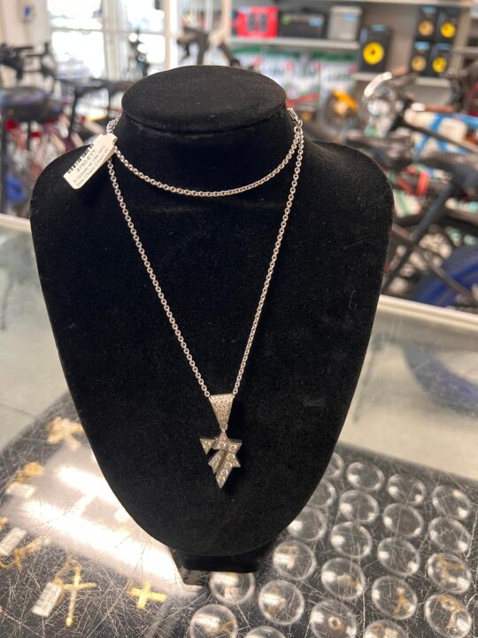 White gold Hai pendant symbolizing life, embellished with diamond details, hanging on a delicate silver chain displayed on a black velvet bust at Dixie Pawn in Hollywood, FL.