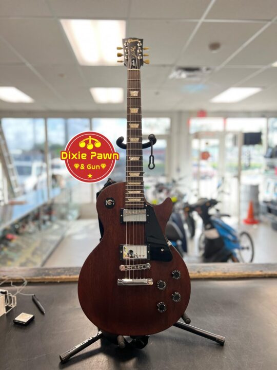 A Gibson Les Paul electric guitar with a wine red satin finish, shown in excellent condition, highlighting its sleek body and premium craftsmanship.