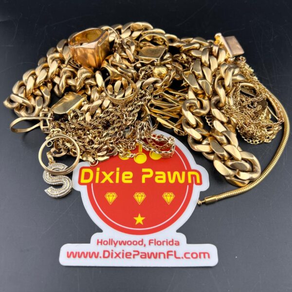 A collection of gold jewelry including chains, rings, and pendants with a Dixie Pawn branded sticker, located in Hollywood, Florida. Visit DixiePawnFL.com for gold buying and selling services.