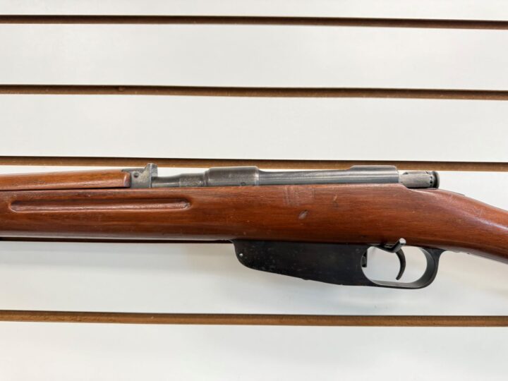 Close up of a Carcano M38 Terni 7.35mm bolt-action rifle receiver, showing the bolt, trigger/trigger guard, and wooden stock with wear.